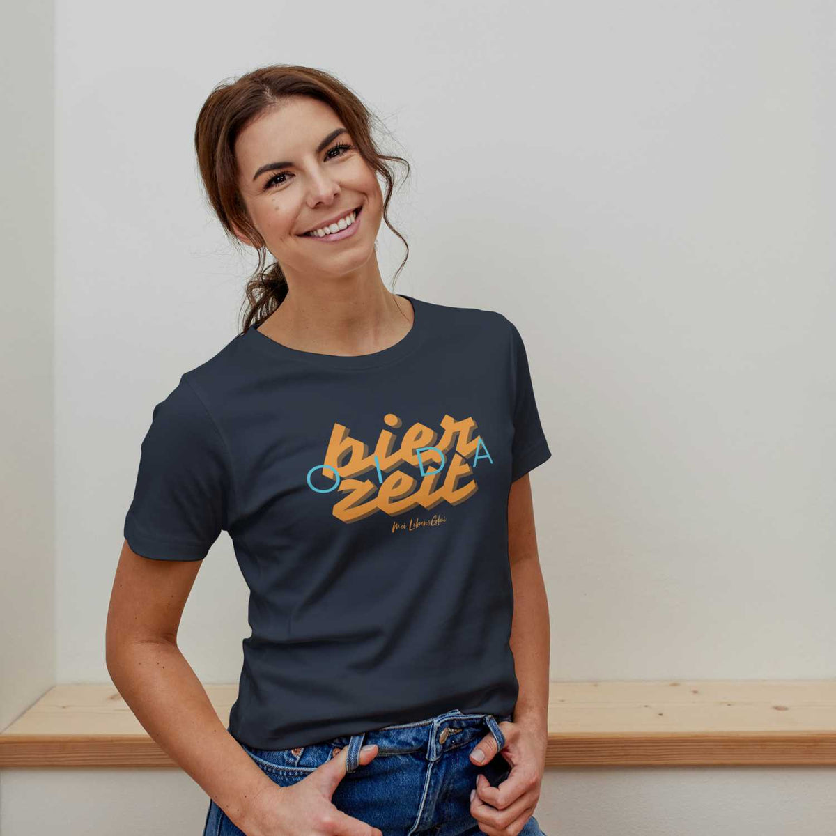 Lächelnde junge Frau präsentiert das marineblaue Damen T-Shirt Bierzeit mit originellem orangefarbenem Schriftzug.