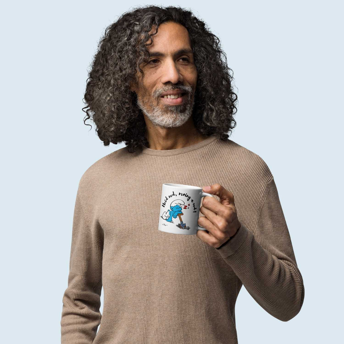 Mann hält Die Schlümpfe Tasse Heid ned, moing a ned mit schlafendem Schlumpf am Spaten.