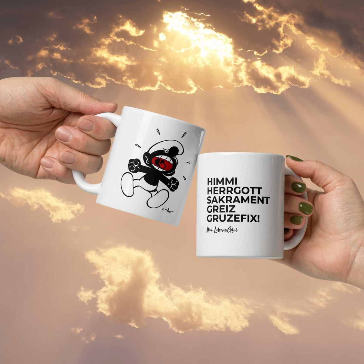 Zwei Hände halten weiße ®Die Schlümpfe Tassen „Himme Herrgott“ mit Motiv und bayerischem Spruch vor Abendhimmel.