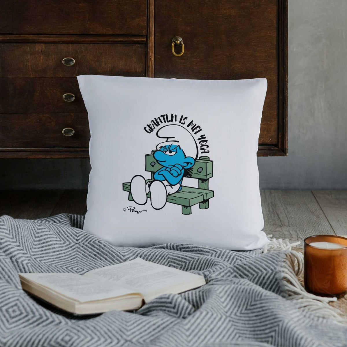 ®Die Schlümpfe Grantln is mei Yoga Kuschelkissen mit Griesgram auf Bank, gelegen auf Decke neben Buch