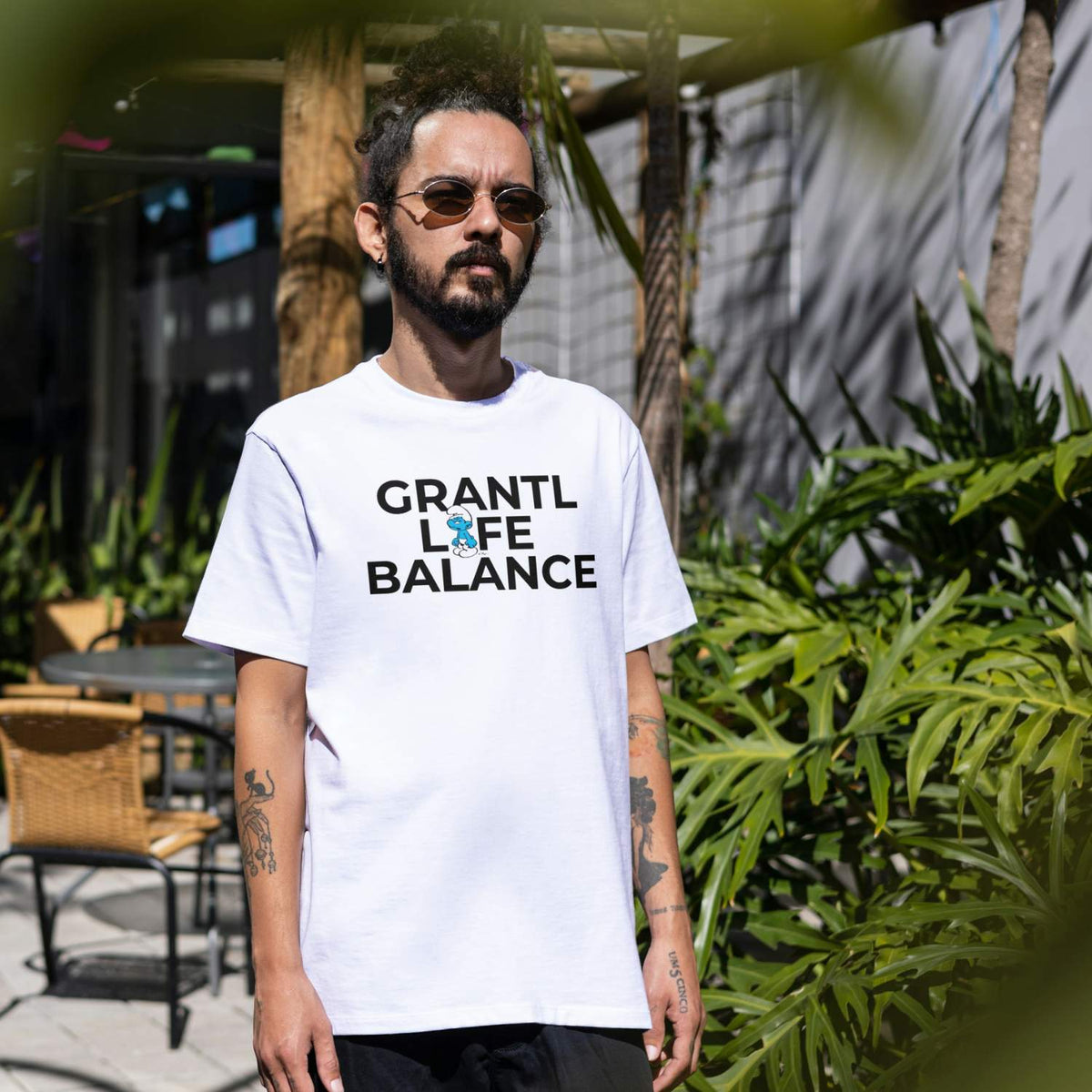 Mann trägt weißes Schlümpfe Herren T-Shirt "Grantl Life Balance" mit Grumpy Schlumpf-Motiv stilvoll im Freien.