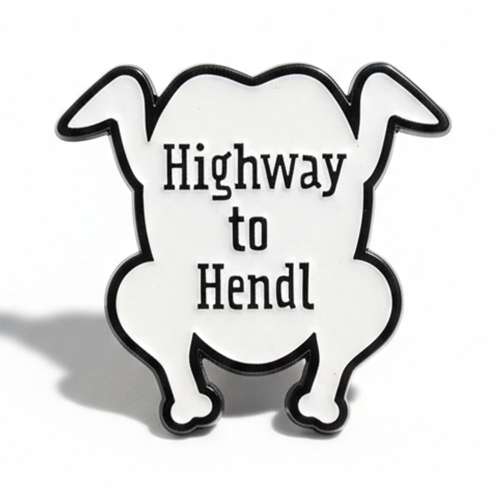 Pin „Highway to Hendl“: weißes Emaille-Brathendl mit schwarzem Schriftzug
