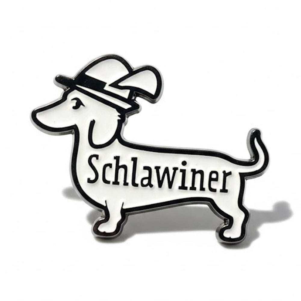 Dackel Pin „Schlawiner“: weißer Emaille-Dackel mit schwarzem Trachtenhut und Schriftzug