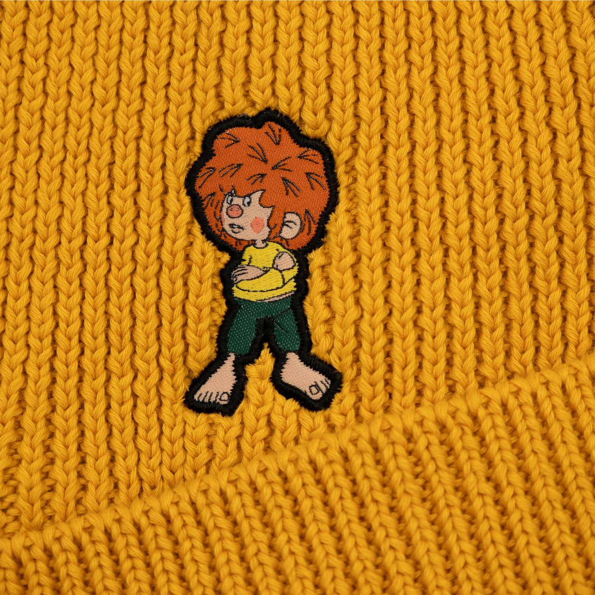 Nahaufnahme der senfgelben Pumuckl Beanie aus Baumwolle mit gesticktem Pumuckl-Motiv.