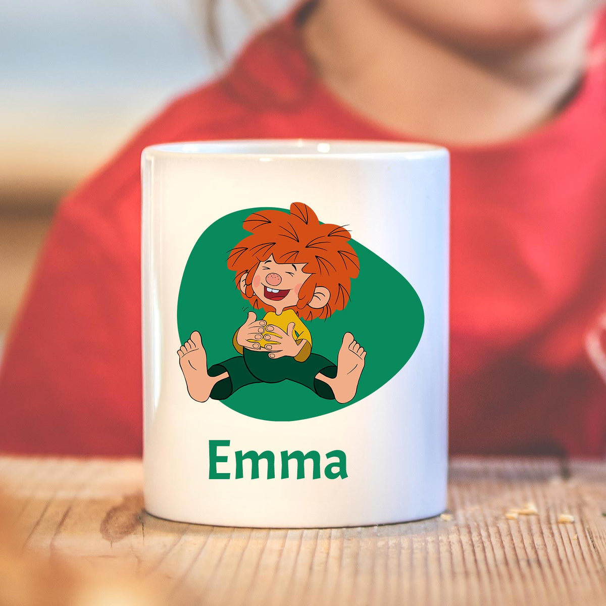 Weiße ®Pumuckl Tasse mit lustiger Zeichnung und individuellem Namensdruck Emma auf Echtholzoberfläche.
