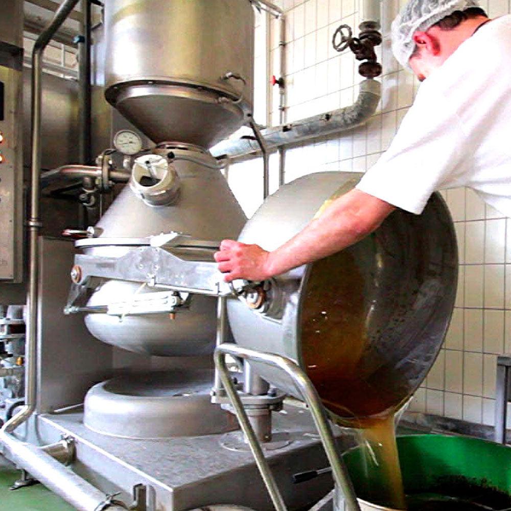 Mitarbeiter befüllt rotierenden Kochkessel mit flüssigem Inhalt, hochmoderne Lebensmittelproduktion.