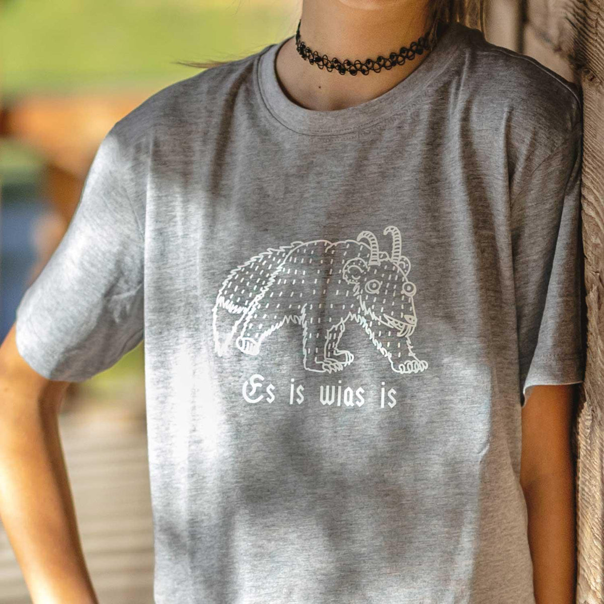 Graues Kinder T-Shirt Wolpertinger Es is wias is mit weißem, detailliertem Druck des Fabelwesens.