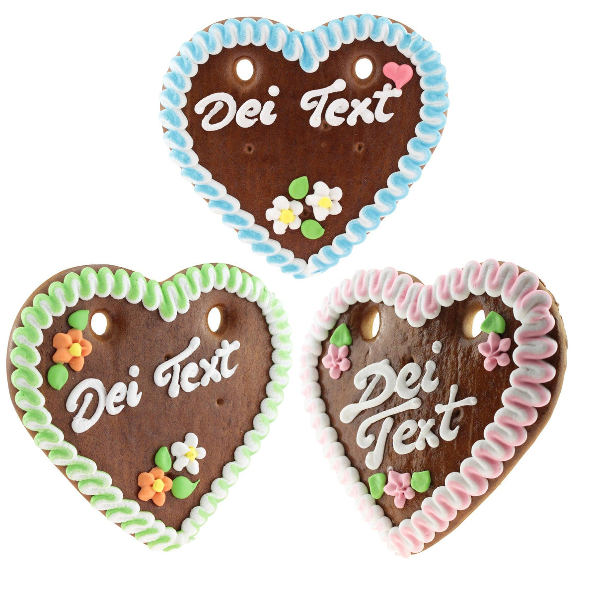 Drei Lebkuchenherzen mit Wunschtext „Dei Text“ in den Randfarben blau, grün und rot mit Zuckerguss-Blümchen