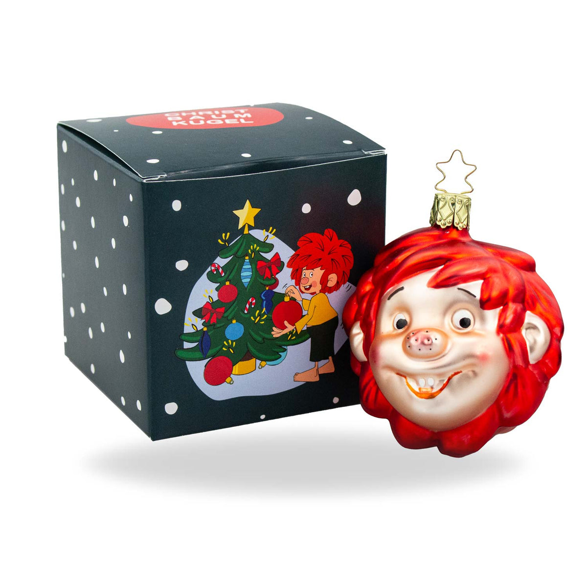 Pumuckl Weihnachtskugel aus Glas, rot-glänzend mit Echthaar-Effekt und goldener Aufhängung vor Geschenkbox.