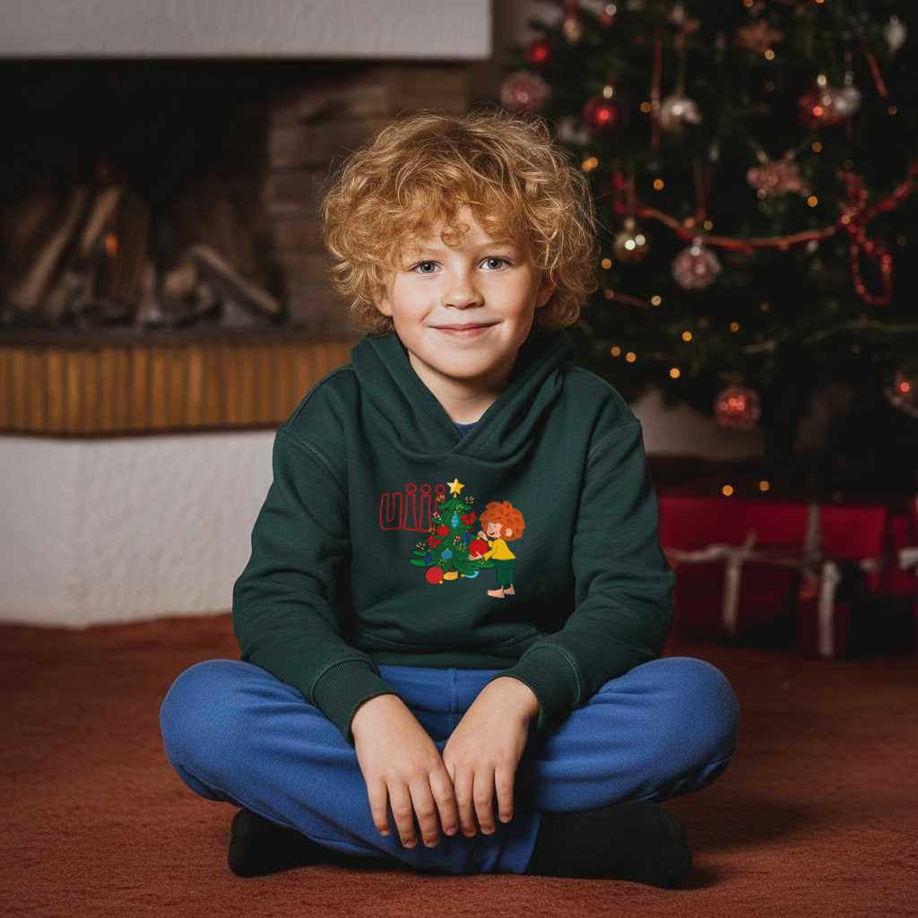 Junge mit blonden Locken im Pumuckl Hoodie für Kinder mit Weihnachtsmotiv „uiii“ vor geschmücktem Baum