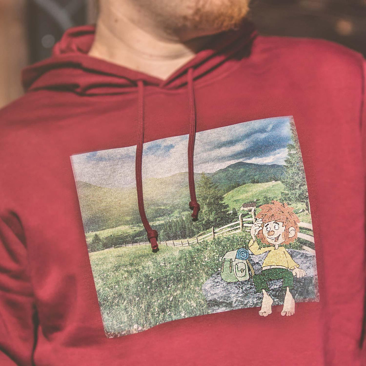Roter ®Pumuckl Herren Hoodie Berg-Kobold mit großem Print von Pumuckl in bergiger Landschaft.