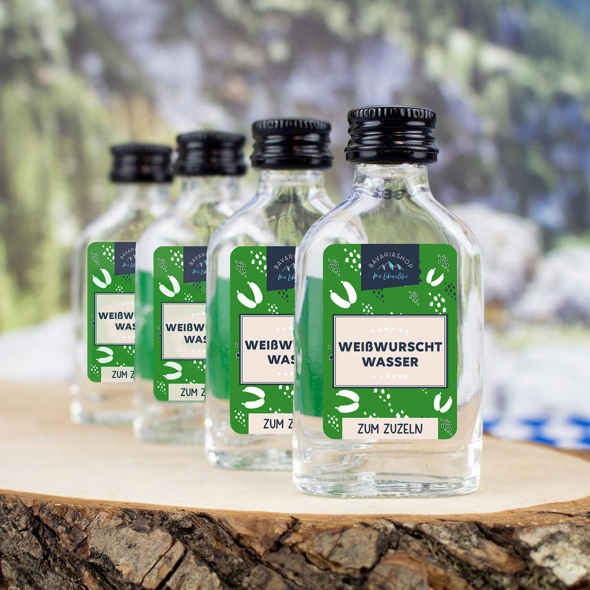 Klarer Obstler in Mini-Glasflasche mit weiß-blauem Etikett und Aufdruck „Weißwurschtwasser“, Inhalt 2 cl.