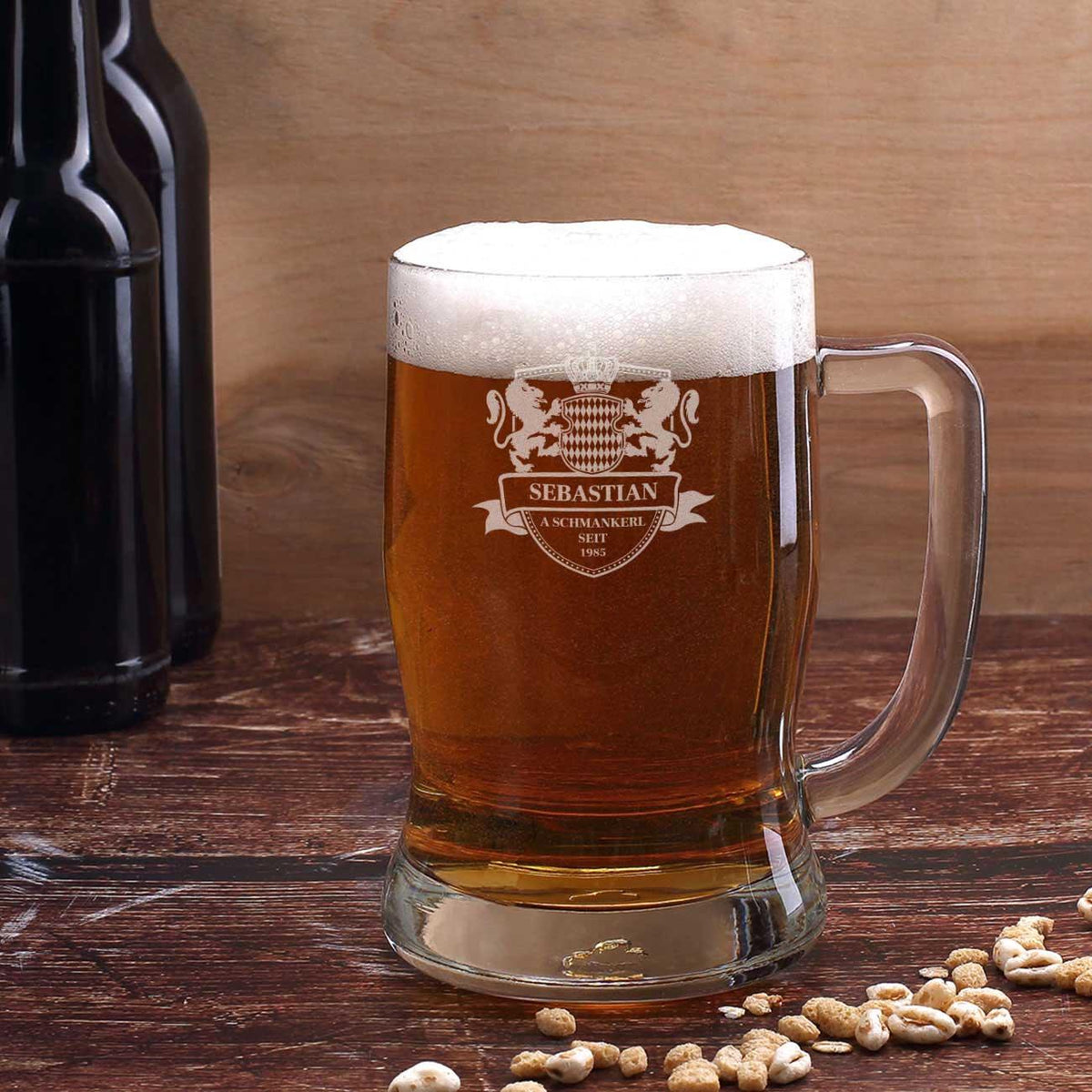 Bayerischer Bierkrug mit individueller Gravur “Sebastian a Schmankerl” und Wappen, gefüllt mit Bier auf Holztisch.