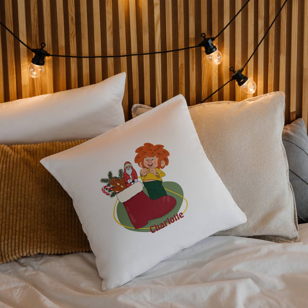Weißes ®Pumuckl Kuschelkissen Nikolaus mit personalisiertem Namen Charlotte und Weihnachtsmotiven auf einem Bett.