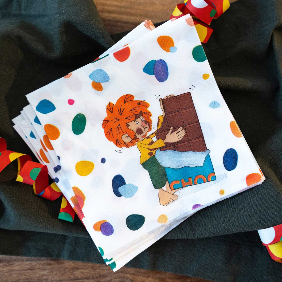 Pumuckl Servietten für den Kindergeburtstag: Pumuckl mit großer Tafel Schokolade auf Papierservietten mit bunten Punkten