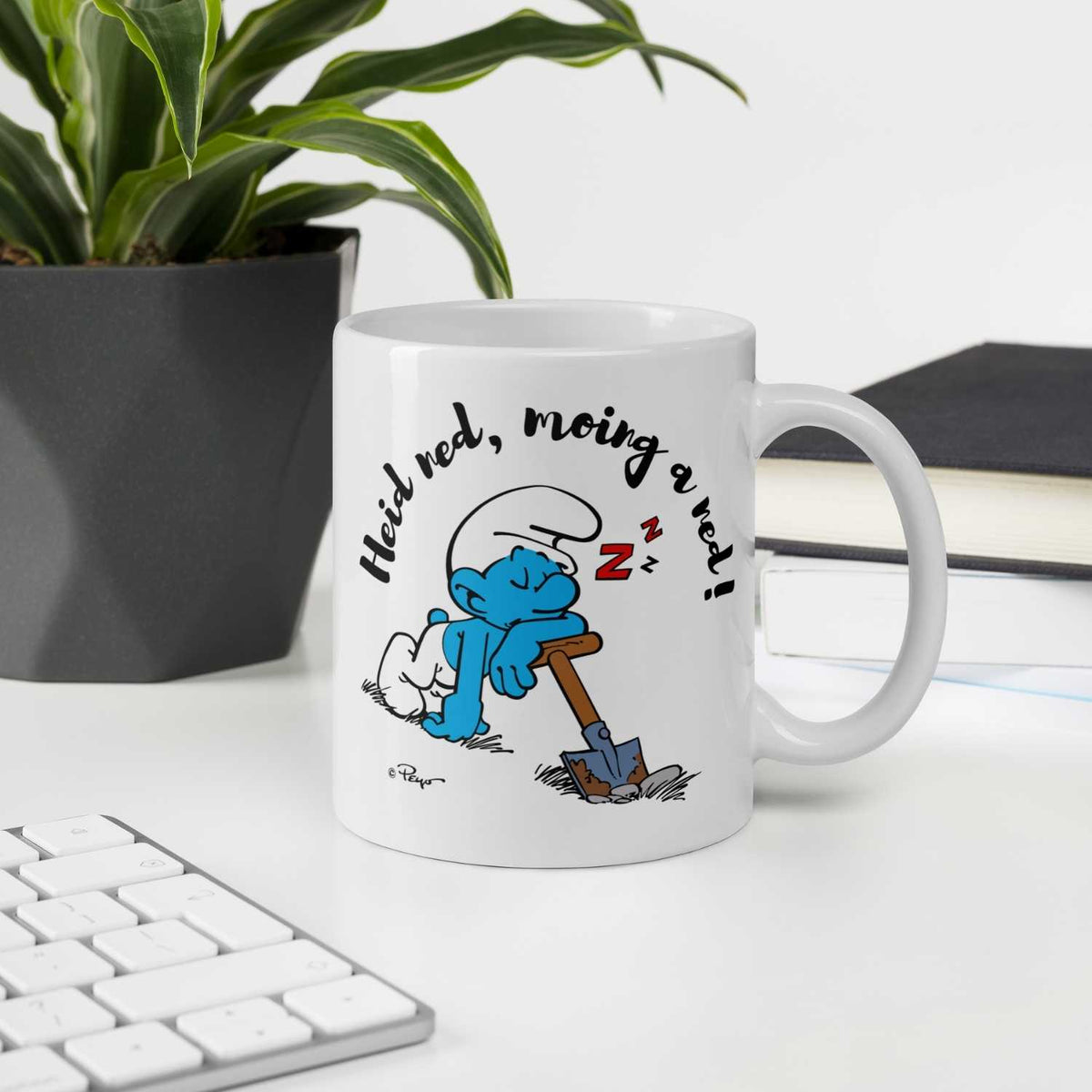 Weiße®Die Schlümpfe Tasse Heid ned, moing a ned mit lachendem Schlumpf, der schlafend auf Schaufel lehnt.
