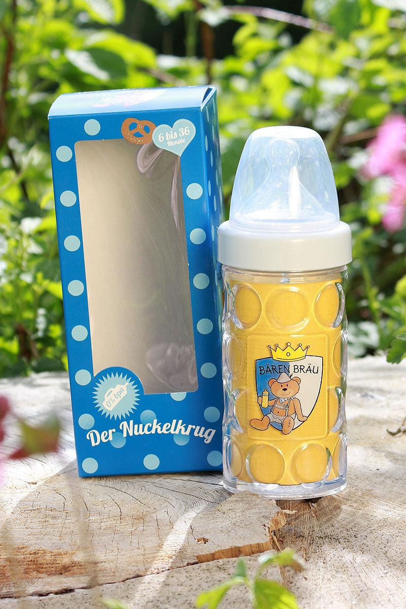 BPA-freier Baby-Nuckelkrug im Bierkrug-Design mit Bären-Emblem und blauer Geschenkverpackung draussen auf Holz.