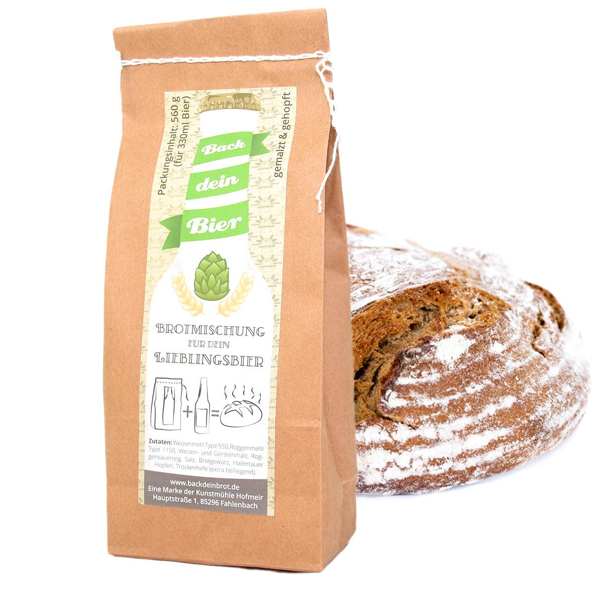 Back dei Bier" Brotmischung Beutel aus Kraftpapier mit Etikett neben einem frisch gebackenen Brot.