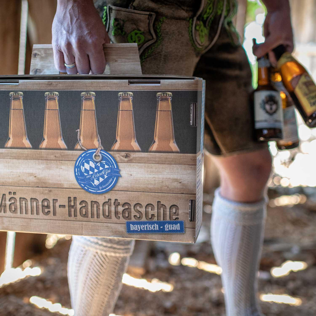Mann in Lederhose trägt die Männerhandtasche mit Bier am Griff
