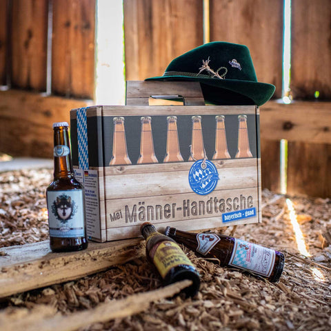 Männerhandtasche mit Bier: Tragekarton in Holzoptik mit Rautenmuster, bayerische Bierflaschen und Trachtenhut auf Holzspänen