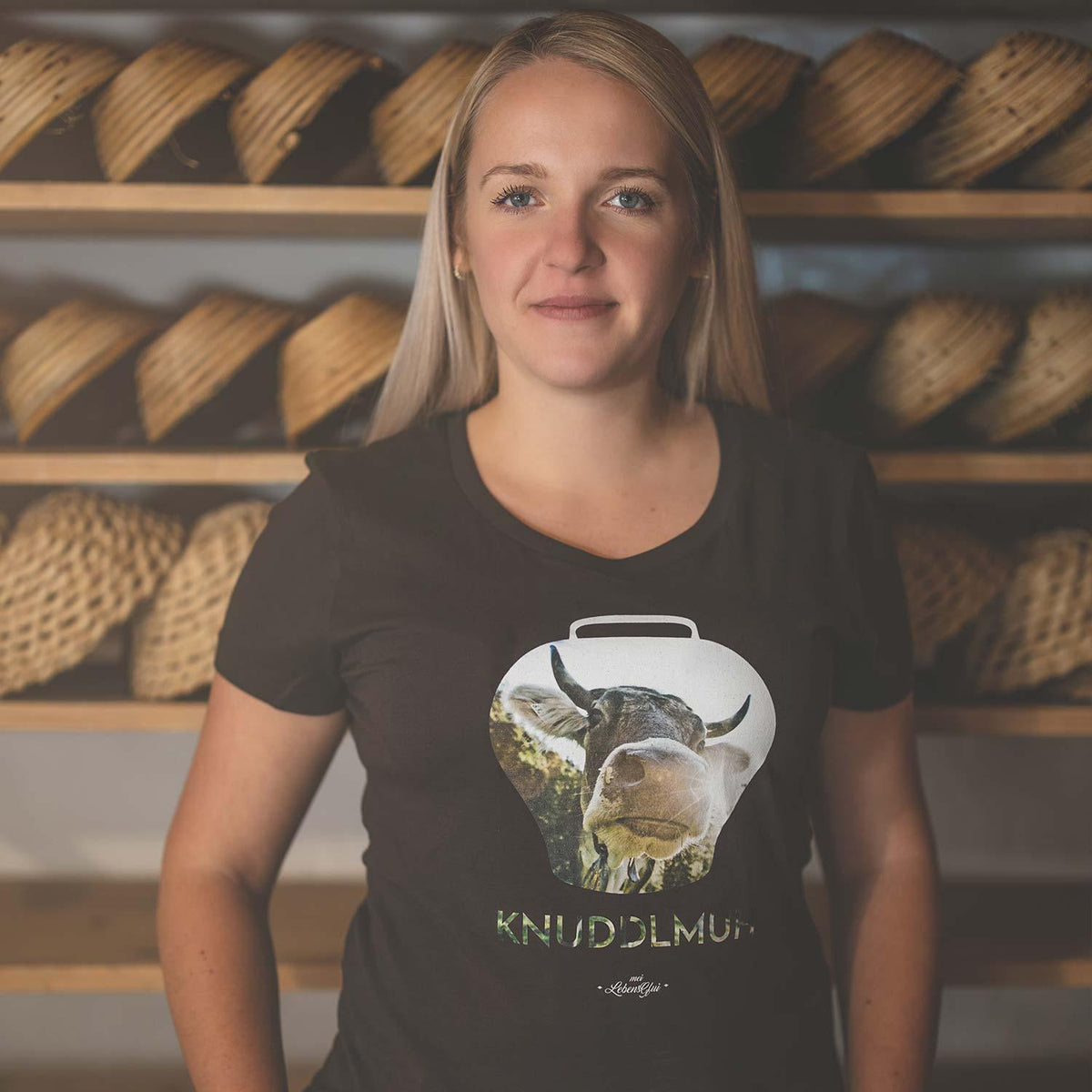 Junge Frau trägt schwarzes Damen T-Shirt Knuddlmuh mit Kuhmotiv in Glockenform, lässig posierend.