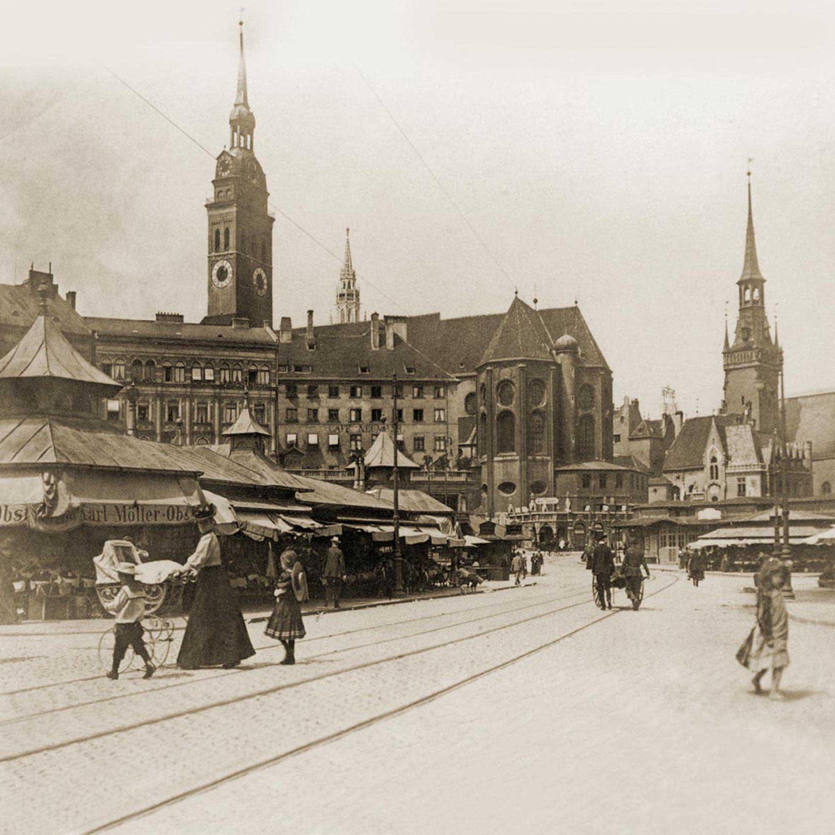 Historische Münchener Straße um 1900 mit Markthütten, Passanten und Kirchengebäuden im Hintergrund.