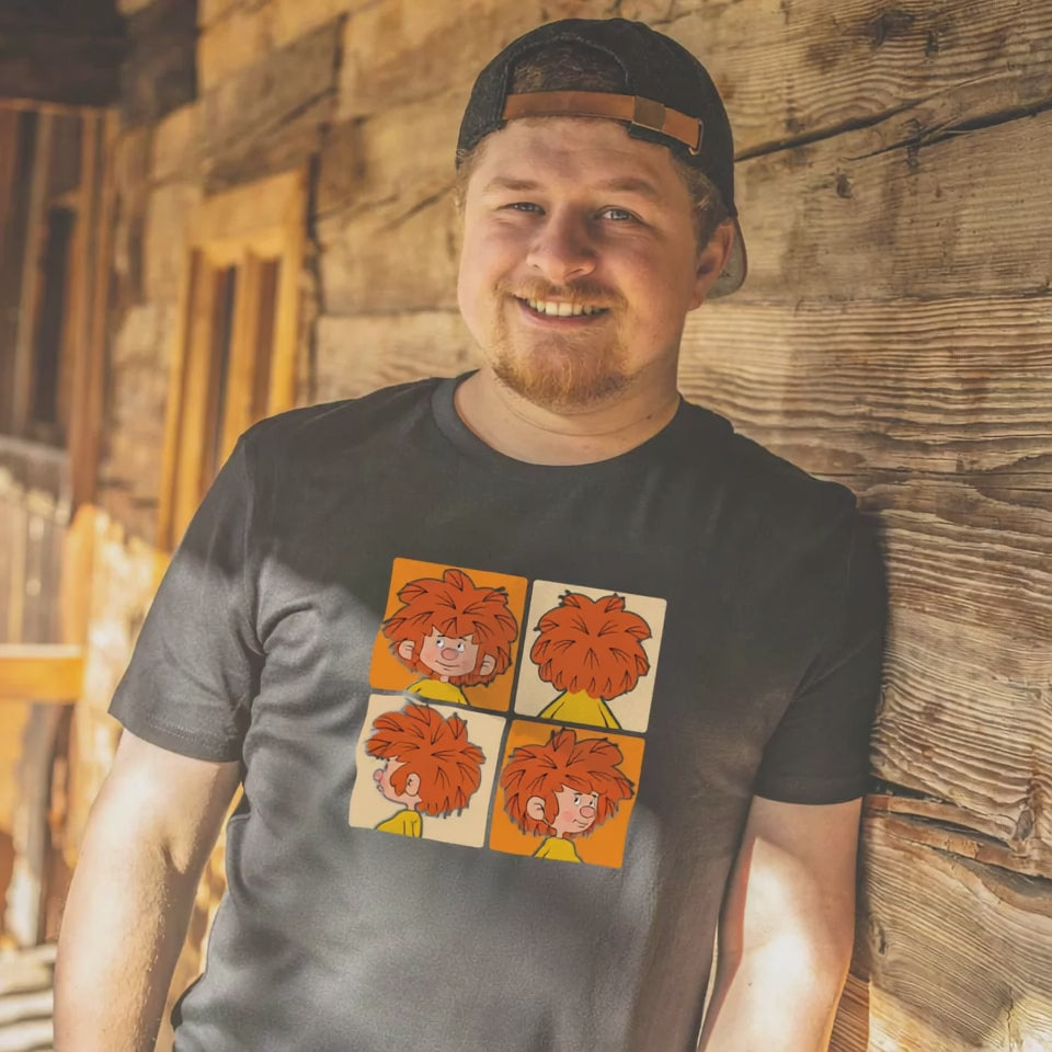 Lächelnder Mann mit Bart und Basecap, trägt ein schwarzes T-Shirt mit vier Pumuckl-Motiven.