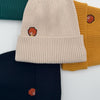Kollektion von Pumuckl Beanies in verschiedenen Farben: beige, senfgelb, dunkelblau und dunkelgrün aus Baumwolle.