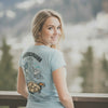 Junge Frau im hellblauen Damen Rezept T-Shirt "Kaiserschmarrn Gang" mit Gebirgsmotiv und Gerichtabdruck.