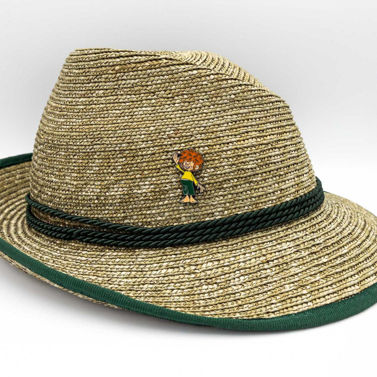 Pumuckl Servus Pin mit dem Kobold beim Winken auf einem beigefarbenen Strohhut.