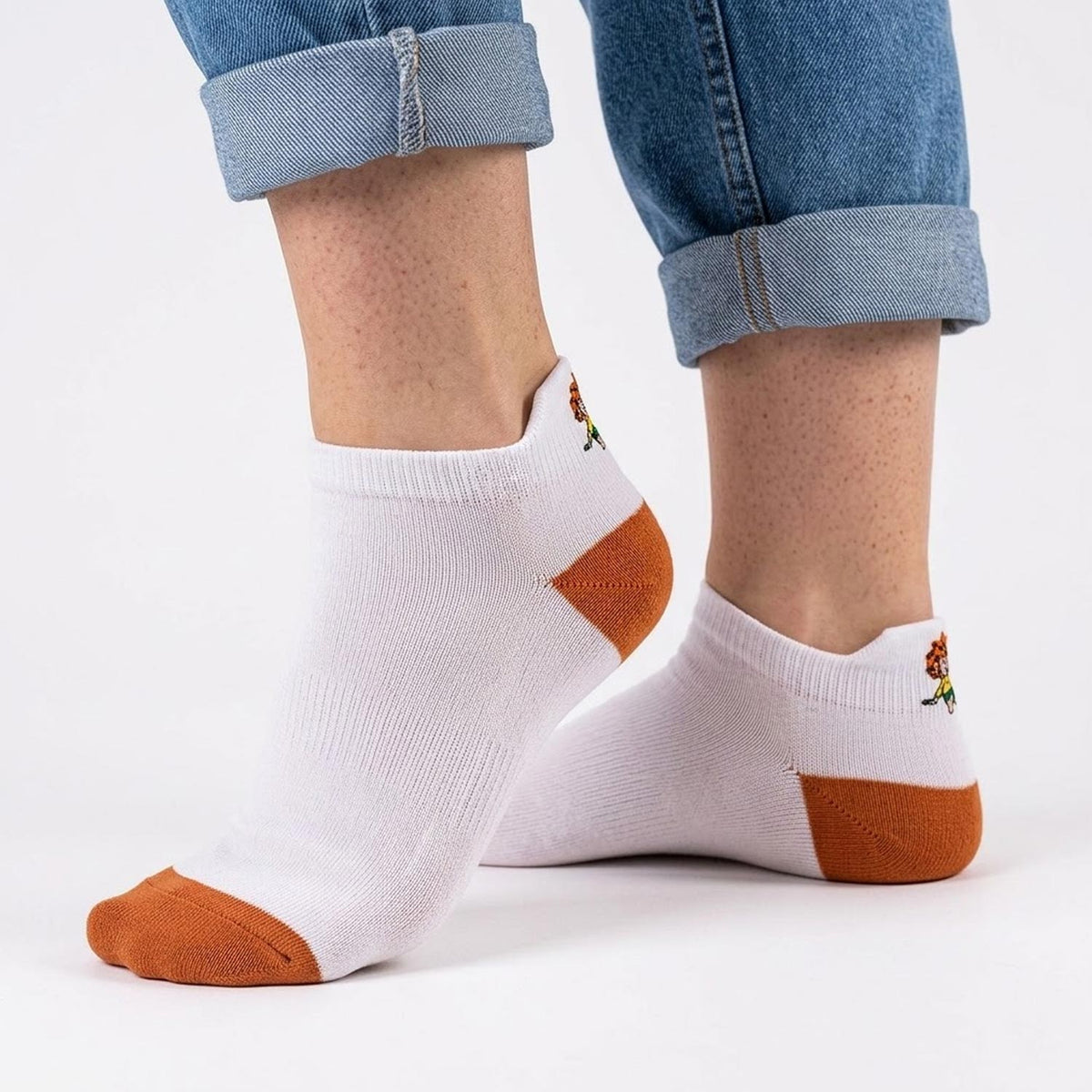 Kurze Pumuckl Sneaker Socken in Weiß mit orangefarbener Ferse und Spitze, seitlich getragen, Pumuckl-Stickerei an der Fersenlasche