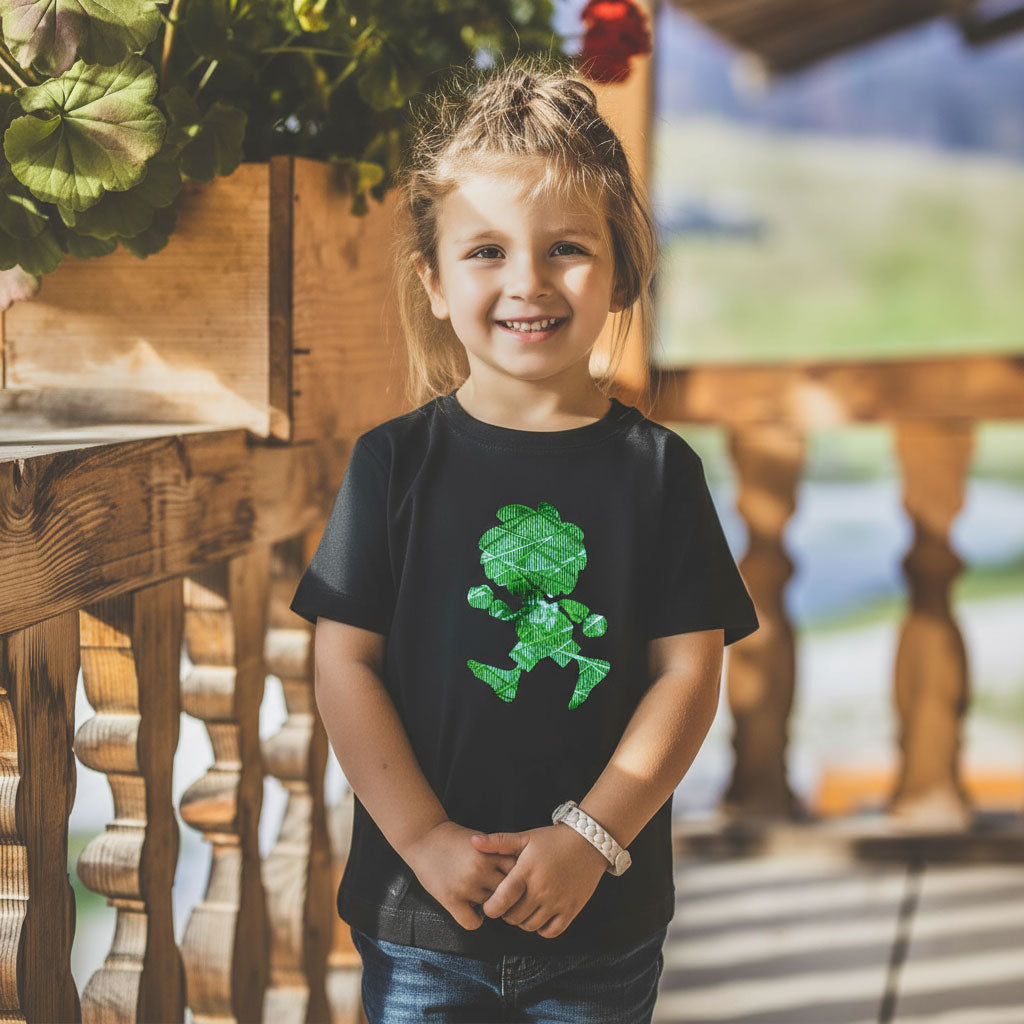 Lachendes Mädchen im schwarzen ®Pumuckl Kinder T-Shirt Ampel-Edition mit grünem Kobold-Motiv auf Balkon.