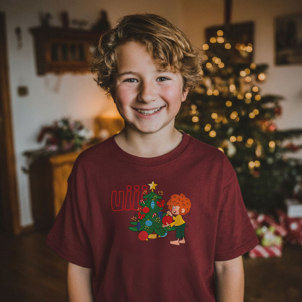 Lachender Junge im weinroten Pumuckl Kinder T-Shirt „uiii Weihnachten“ vor dem Christbaum – Weihnachtsshirt für Kinder