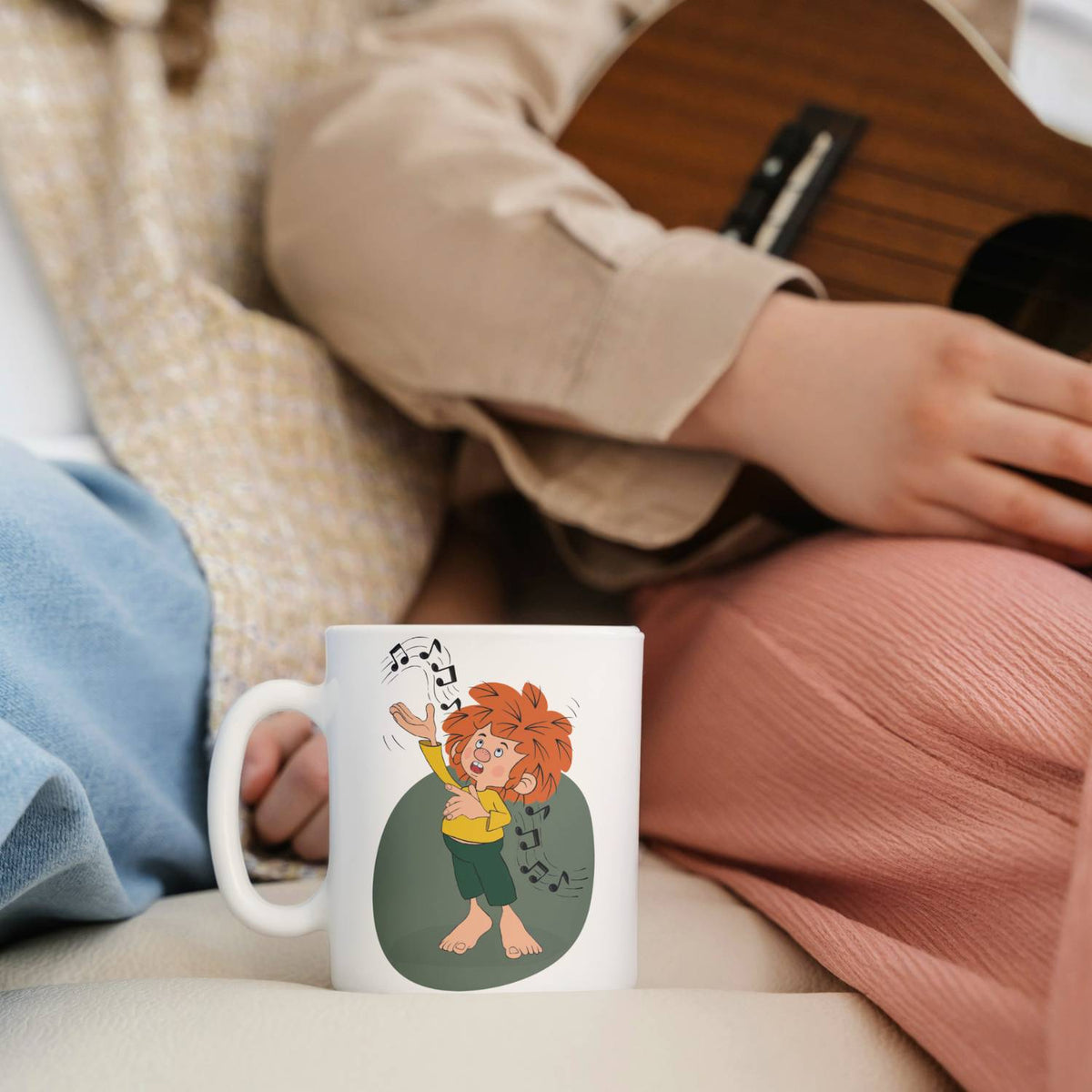 Weiße Pumuckl Tasse Musik mit freudigem Kobold und Noten, daneben eine Person mit Ukulele.