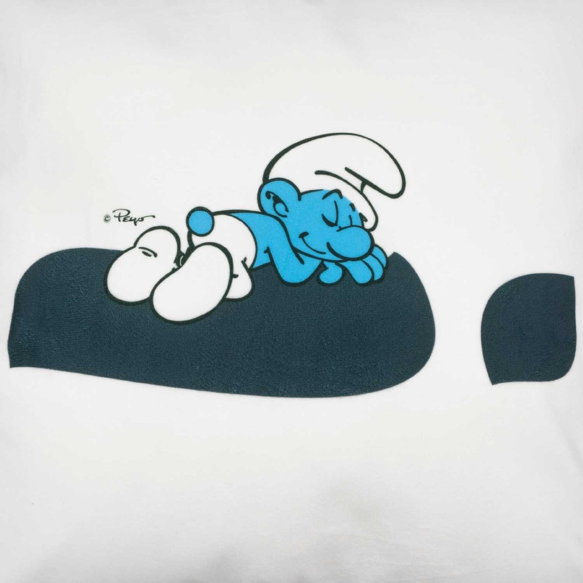 Die Schlümpfe "Ausruhezeichen" Kuschelkissen mit Schlumpf schlafend auf dunklem Kissen vor weißem Hintergrund.
